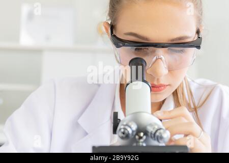 Schöne Wissenschaftlerinnen betrachten die Mikroskope in einem Wissenschaftslabor mit verschiedenen Geräten im Labor. Stockfoto
