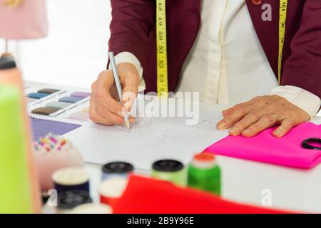 Ältere Designer, die auf Papier skizzieren, um Kleidung zu entwerfen Stockfoto