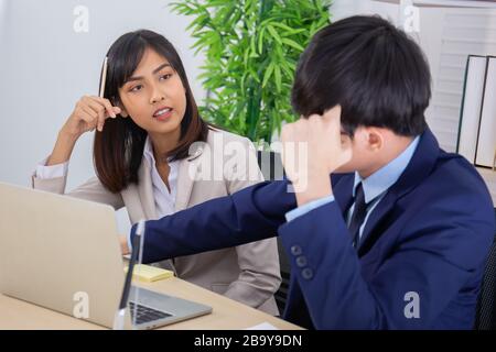 Zwei männliche und weibliche Asiaten halfen, einen Tisch voller Dokumente und Tablets, Notizbücher zu planen. Stockfoto