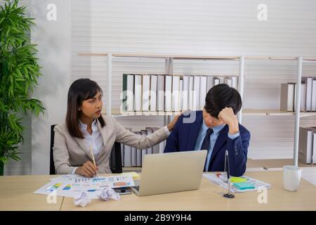 Eine asiatische weibliche Führungskraft tröstete und jubelte über einen traurig aussehenden männlichen Mitarbeiter. Stockfoto