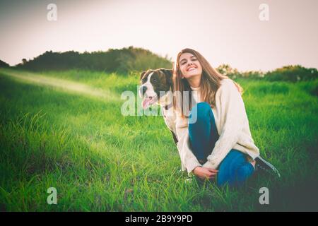 Junge Frau, die mit American Staffordshire Terrier sitzt Stockfoto