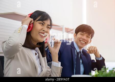 Zwei asiatische Männer- und Büroangestellte knecken sich im Büro lustig zusammen. Stockfoto