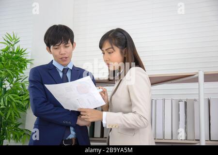 Zwei asiatische Geschäftsleute und Frauen stehen im Büro zusammen, in der Hand, die die Dokumente hält. Stockfoto