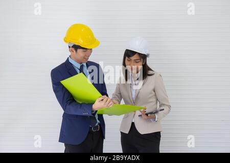 Zwei asiatische Männer- und Vorarbeiter, die einen Helm tragen und am Veranstaltungsort stehen und sprechen Stockfoto