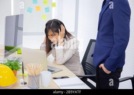 Frustriert betonte junge asiatische Geschäfte mit der Deckung werden Spitzhand-Chef am Arbeitsplatz. Stockfoto