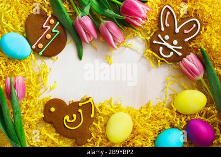 Osterhintergrund. Lebkuchen in Form von farbigem Osterkaninchen, Küken und Ei auf weißem Holzhintergrund Stockfoto