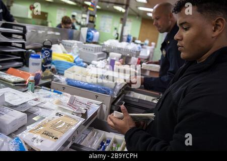 Los Angeles, Kalifornien, USA. März 2020. Hospitalman Jeremiah Lewis aus San Antonio organisiert am 24. März 2020 medizinische Versorgung an Bord des Militärsealift Command Hospitalschiff USNS Mercy (T-AH 19). Mercy wird zur Unterstützung der COVID-19-Reaktionsbemühungen des Landes eingesetzt und dient als Überweisungskrankenhaus für nicht-COVID-19-Patienten, die derzeit in Krankenhäusern am Land eingeliefert werden. So können Landkrankenhäuser ihre Bemühungen auf COVID-19-Fälle konzentrieren. Eine der Missionen des Verteidigungsministeriums ist die Verteidigungsunterstützung von Zivilbehörden. DoD unterstützt die Federal Emergency Management AG Stockfoto