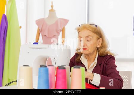 Professionelle Designerinnen nähen mit kleinen Nähmaschinen auf dem Tisch. Stockfoto