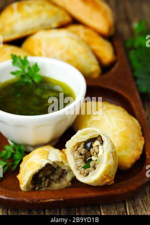 Empanadas mit Schimichurri auf Holztisch Stockfoto
