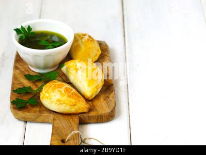 Empanadas mit Schimichurri auf Holztisch Stockfoto