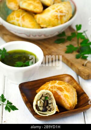 Empanadas mit Schimichurri auf Holztisch Stockfoto