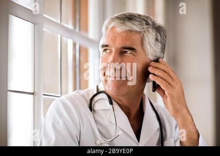 Portrait von männlicher Arzt über sein Mobiltelefon. Stockfoto