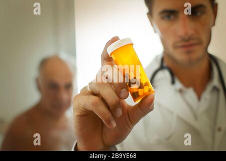 Doktor, der eine Flasche Pillen mit einem besorgten Blick auf sein Gesicht aufhält. Stockfoto