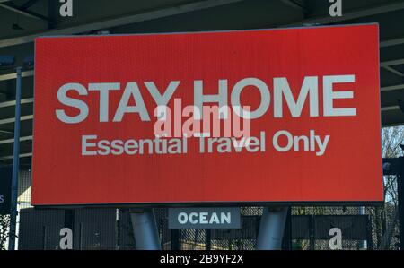 Ein großes, beleuchtetes Schild in Manchester, Großbritannien, sagt Passanten, dass sie "Day Home Essential Travel Only" im Hinblick auf den aktuellen globalen Ausbruch des neuartigen Coronavirus, Covid 19-Infektion, erreichen Stockfoto