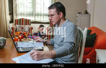 Vater arbeitet zu Hause, während ihr Sohn spielt Stockfoto