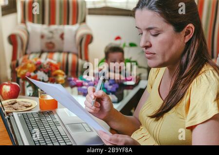 Mutter arbeitet zu Hause, während ihr Sohn spielt Stockfoto