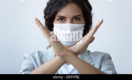 Junge Frau in medizinischer Maske zeigt eine Handgeste der Pandemie Stockfoto