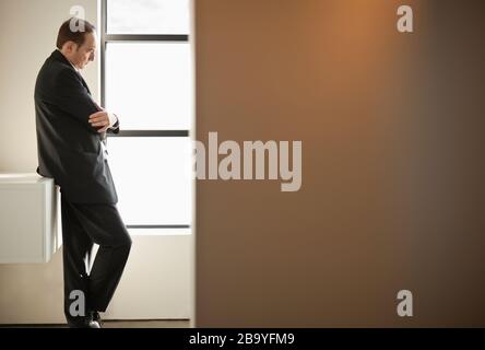 Geschäftsmann lehnt Arme in Gedanken gefaltet. Stockfoto