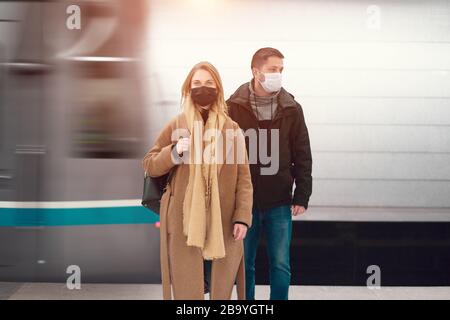 Mann und Frau in medizinischen Masken stehen in der Nähe des Autos in der U-Bahn. Coronavirus Epidemie. Stockfoto