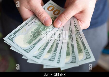 Dollar in den Händen des Mannes. Gewinne, Ersparnisse. Erfolg, Motivation, Finanzströme, Wohlstand. Stapel von Dollars. 100 US-Dollar Stockfoto