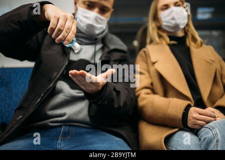 Junger Mann und Frau, die im U-Bahn-Auto antiseptisch sitzen. Coronavirus Epidemie Stockfoto