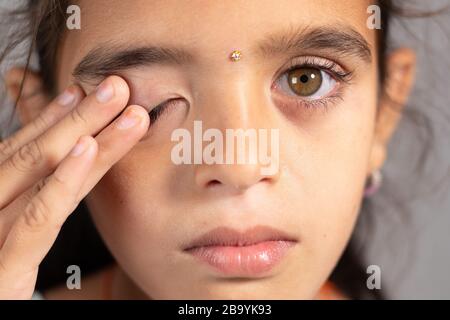 Extreme Nahaufnahme des Kindes, das die Augen reibt - ein Konzept, das zeigt, dass Sie Ihre Augen nicht berühren und nicht berühren. Schutz vor COVID-19- oder Coronavirus-Infektionen Stockfoto