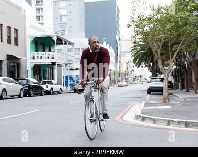 Afroamerikanischer Mann fährt mit seinem Fahrrad auf der Straße der Stadt Stockfoto