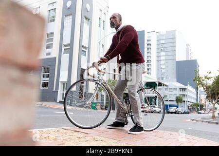 Afroamerikanischer Mann sitzt auf seinem Fahrrad in der Straße der Stadt Stockfoto