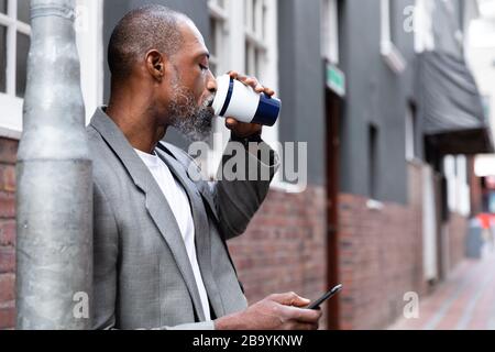 Afroamerikanischer Mann mit seinem Telefon auf der Straße Stockfoto