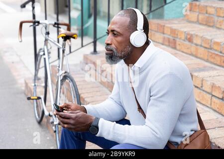 Afroamerikanischer Mann sitzt auf einer Treppe und hört Musik Stockfoto