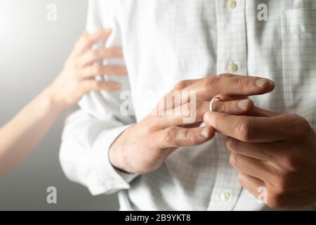 Ein Mann zieht einen Ehering von seinem Finger. Der Mann betrügt seine Frau. Das Konzept des Verrats. Stockfoto