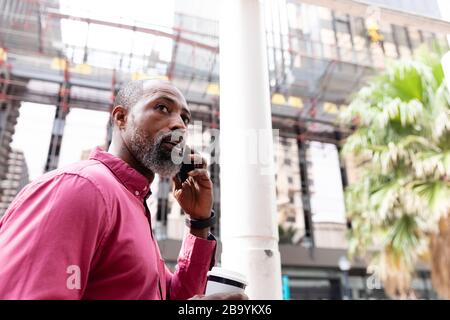 Afroamerikanischer Mann mit seinem Telefon auf der Straße Stockfoto