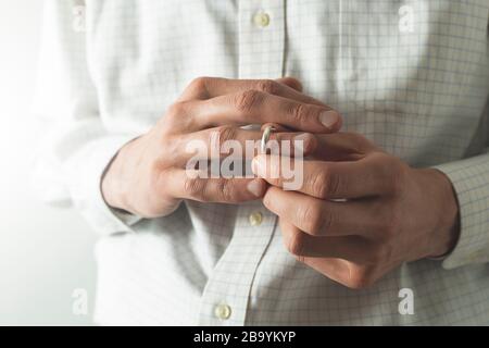 Ein Mann zieht einen Ehering von seinem Finger. Der Mann betrügt seine Frau. Das Konzept des Verrats. Stockfoto