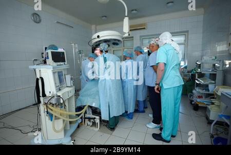 Chirurgen in Gesichtsmasken, die um die Patientenplatte stehen und eine Operation durchführen, eine künstliche Beatmungsmaschine für die Lunge. Januar 2019. Kiew Stockfoto