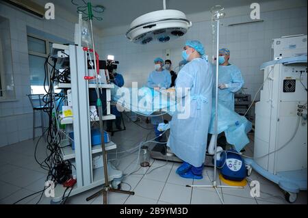 Chirurgen in Gesichtsmasken, die um die Patientenplatte stehen und eine Operation durchführen, eine künstliche Beatmungsmaschine für die Lunge. Januar 2019. Kiew Stockfoto