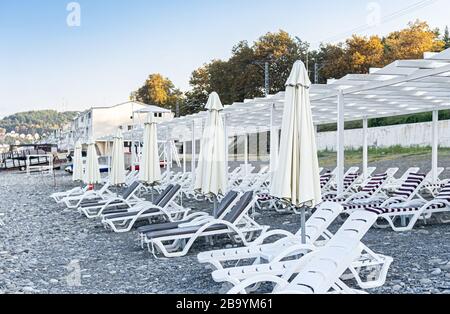 Leerer Strand mit Sonnenliegen und geschlossenen Sonnenschirmen beim Ausbruch des Covid 19-Virus. Quarantänekonzept. Die Krise des Tourismusgeschäfts. Stockfoto