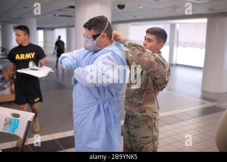 Mitglieder der Nationalgarde von Puerto Rico bereiten sich darauf vor, ankommende Passagiere für die COVID-19, Coronavirus auf dem internationalen Flughafen San Juan am 24. März 2020 in San Juan, Puerto Rico, zu belaufen. Stockfoto