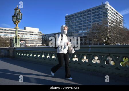 Eine Frau, die einen Facemask trägt, läuft am St Thomas's Hospital in London vorbei, nachdem Premierminister Boris Johnson die Entscheidung getroffen hatte, Großbritannien in eine Sperrstelle zu setzen, um die Ausbreitung des Coronavirus einzudämmen. Stockfoto