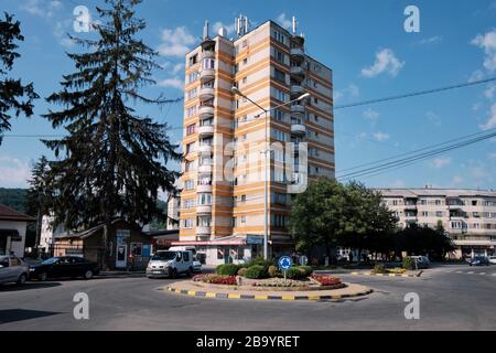 Zehnstöckiger, mit ockerfarbenen Streifen gestalter, brutalistischer Wohnblock aus Beton und runde Balkone am Kreisverkehr in Sighetu Marmatiei Rumänien Stockfoto