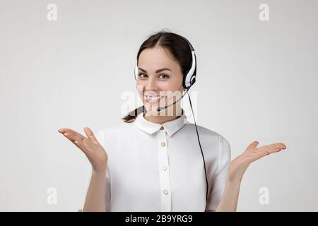 Schöne lächelnde Frau Beraterin des Callcenters in Kopfhörern auf grauem Hintergrund, weibliche Kundenbetreuerin mit Headset Stockfoto