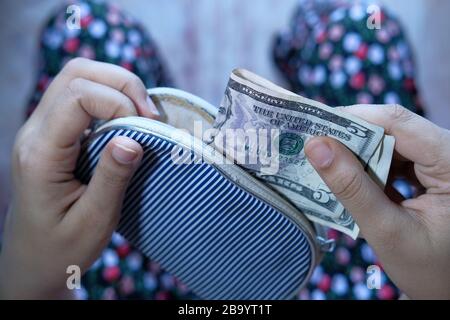 Frau, die US-Dollar-Rechnungen aus ihrer Brieftasche herausnimmt Stockfoto