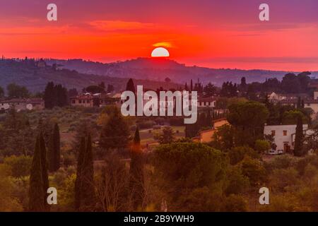 Klassische toskanische Landschaft mit der warmen Sonne bei Sonnenuntergang, die die grünen Hügel, die Becken, die Kiefern und die Villen beleuchtet Stockfoto