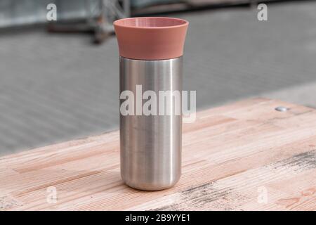 Persönlicher Kaffee Thermobecher auf Picknicktisch mit Holz während einer Wanderung. Stockfoto