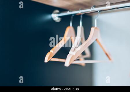 Leere Holzaufhängungen auf der Schiene im schrank. Lifestyle-Komposition mit natürlichem Licht und Kopierraum Stockfoto