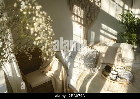 Gemütliches sonniges Schlafzimmer im Boho-Stil mit Licht und Schatten und einer Nahaufnahme weißer Zigeuner-Blumen. Authentisches, lebendes Interieur Stockfoto