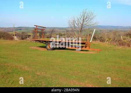 Gesessen geparkt in der Ecke eines Feldes sitzt dieser schwere Anhänger auf den Heuballen, die er normalerweise von Feld zu Hof transportiert. Stockfoto