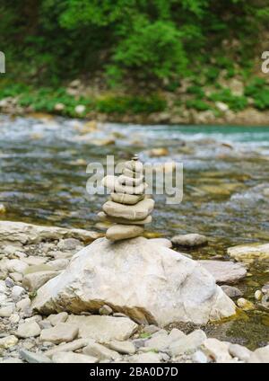 Eine Pyramide aus flachen Steinen am Ufer des schönen Bergflusses Khosta in einem Eibenkastenhain. Selektiver Fokus Stockfoto