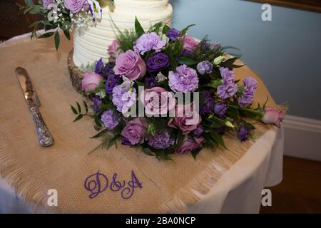 Der Blumenstrauß sitzt neben dem Hochzeitstorte. Rosafarbene Rosen und Nelken im Blumenstrauß der Bräute Stockfoto