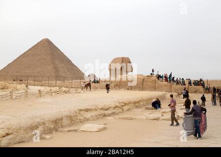 Souvenirhändler und Touristen an der großen Sphinx von Gizeh, in der Nähe der großen Pyramide, auf dem Giza-Plateau in Kairo, Ägypten. Stockfoto