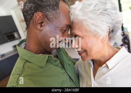 Älteres afroamerikanisches Paar kuschelnd in der Küche Stockfoto